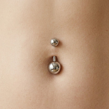 Young American woman midsection wearing the plain titanium navel ring. Perfect flush fit seated against healthy skin with no visible curved bar. 14G 3/8" length.