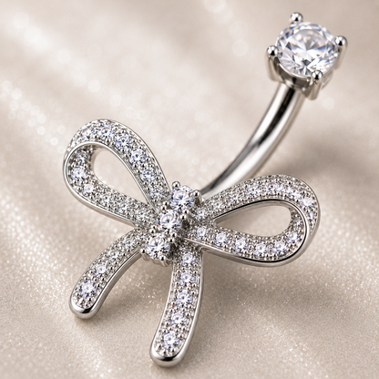 Macro shot of Dazzling Titanium Bow Belly Button Ring showing 3 vertically-aligned CZ stones, left tail shorter than right, polished titanium shine