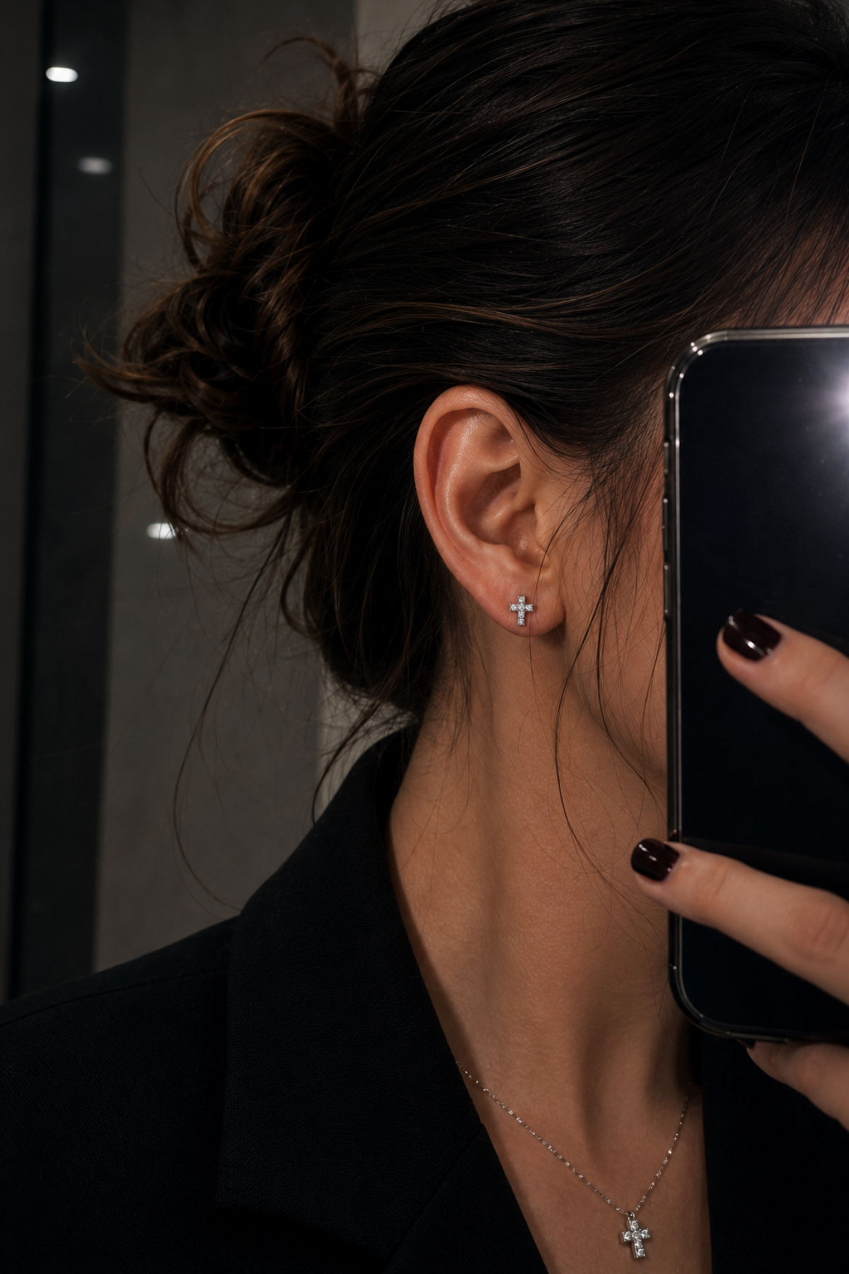 Young woman wearing titanium cross flat back stud earring in a luxury minimalist ear styling look
