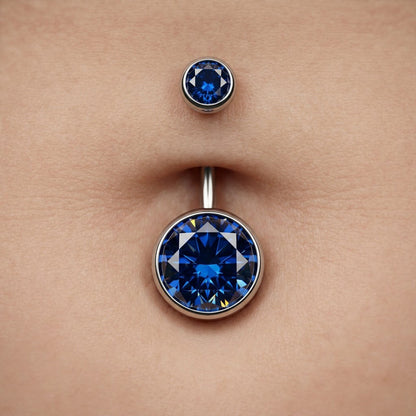 Close-up of high-clarity sapphire blue zircon navel ring on skin, premium titanium body jewelry for women