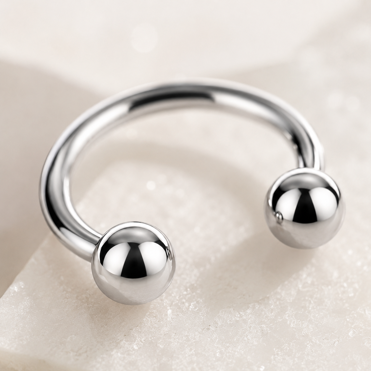 Macro detail of mirror polished titanium horseshoe nose ring with smooth ball ends