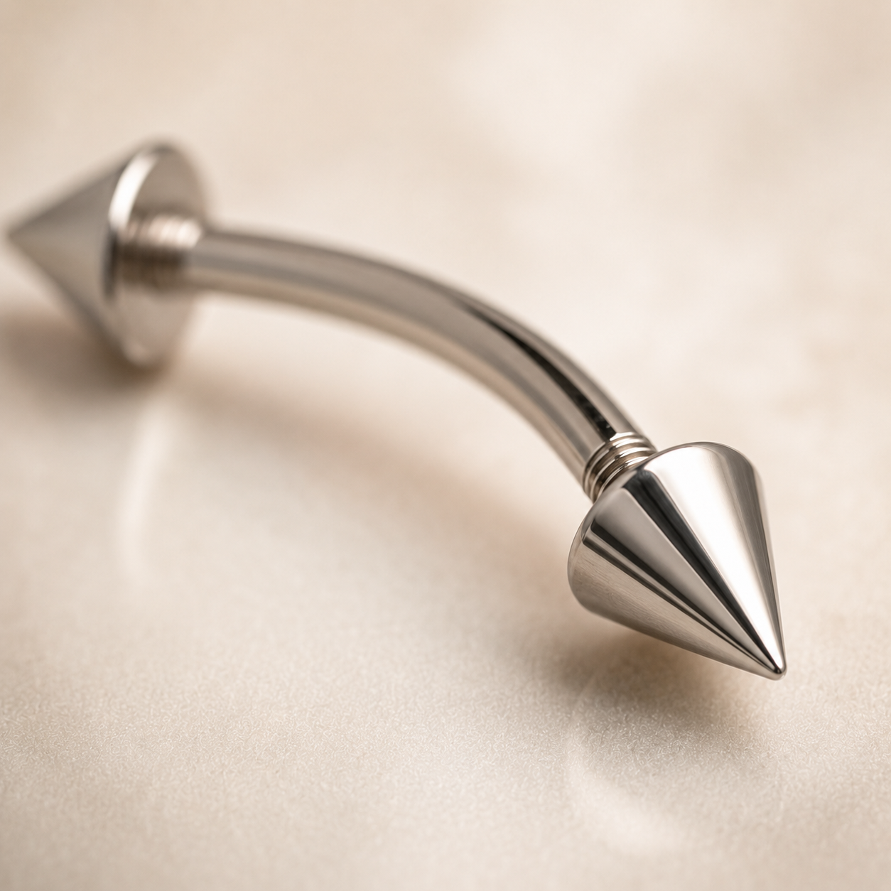 Close up of polished titanium spike curved barbell with cone ends and smooth curved bar
