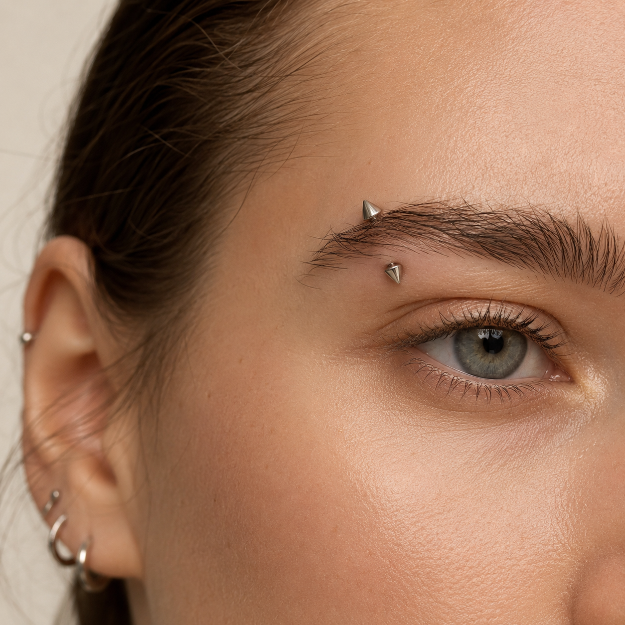 Young woman wearing a titanium spike curved barbell eyebrow piercing with a clean modern look