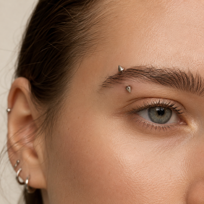 Young woman wearing a titanium spike curved barbell eyebrow piercing with a clean modern look