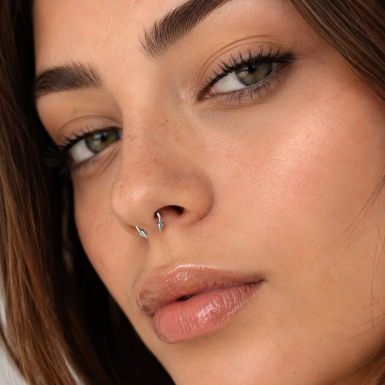 Young woman wearing titanium spike horseshoe nose ring with clean minimal styling and natural skin texture
